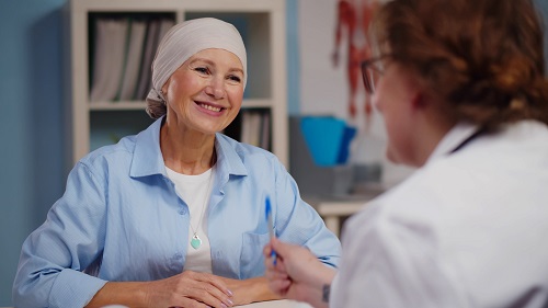 Fotografía en la que una paciente con cáncer mira sonriente a su psicóloga