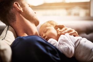 Padre dormido en el sofá con un bebe dormido en brazos