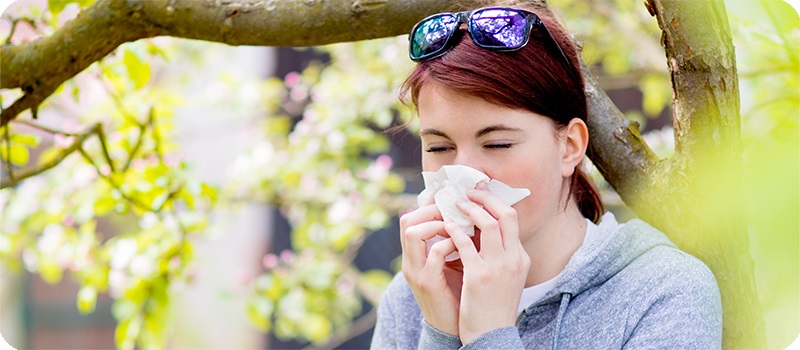 Mujer sonándose la nariz tras un estornudo en la época de alergia primaveral.